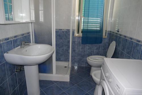 斯卡莱阿Parco Meridiana的蓝色瓷砖浴室设有水槽和卫生间