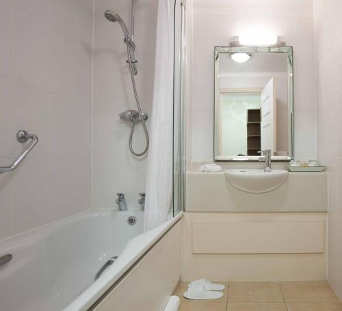 埃尔斯特里The Manor Elstree的带淋浴和盥洗盆的白色浴室