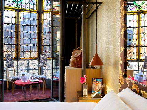 巴塞罗那Axel Hotel Barcelona - Adults Only的一间设有彩色玻璃窗和桌子的房间