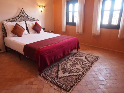 瓦尔扎扎特布舍多摩洛哥传统庭院住宅的一间卧室配有一张带红色毯子和地毯的床。