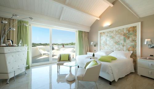 锡拉库扎Wellness Spa Hotel Principe Fitalia的一间带白色床和桌子的卧室以及一个阳台
