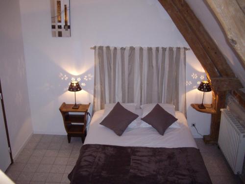 Bernières-sur-Mer吕泽尔恩宾馆的一间卧室配有带两个枕头的床和窗户