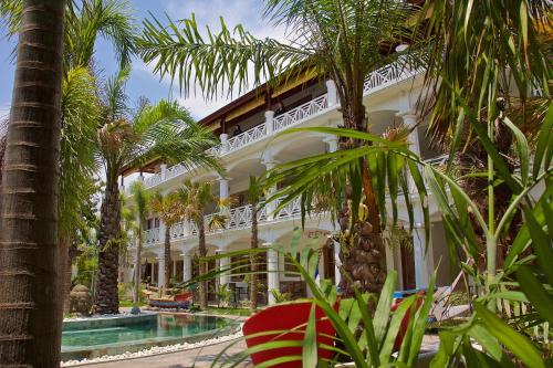 八丹拜OK潜水度假酒店及Spa的一座白色的大建筑,设有游泳池和棕榈树