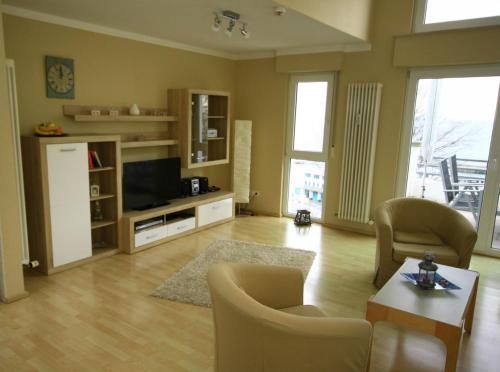 萨斯尼茨Appartementhaus Victoria的客厅配有电视、沙发和椅子