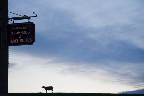奥德斯希尔德Texel Suites的挂着牛的标牌站在山顶