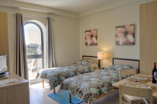 San Ġwann卡帕拉酒店的一间卧室设有两张床和大窗户