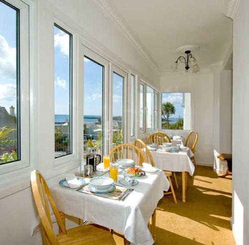 西卢港Seaview的一间设有白色桌椅和窗户的用餐室