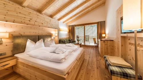 修希Dolmites Nature Hotel Vigilerhof的一间带两张床铺的卧室,位于带木墙的房间内