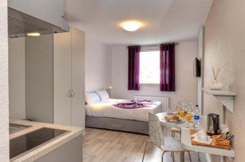 斯特拉斯堡斯特拉斯堡中心城市公寓式酒店的小房间设有床、桌子和厨房