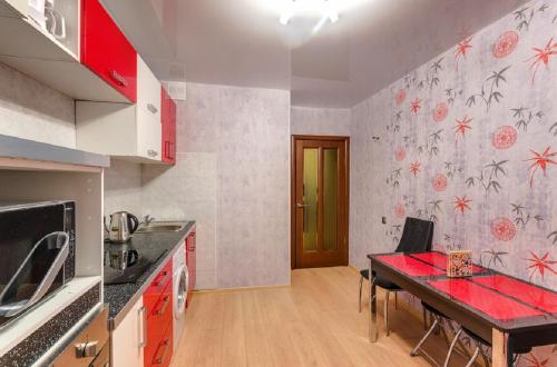 沃罗涅什ATLANT Apartments 106的厨房配有桌子和红色台面
