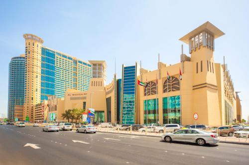 阿布扎比Grand Millennium Al Wahda Hotel and Executive Apartments Abu Dhabi的一条城市街道,汽车停在大楼前