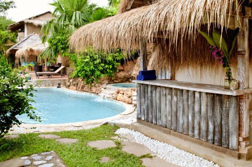 白马市海滨别墅酒店的一个带游泳池和草屋的度假胜地