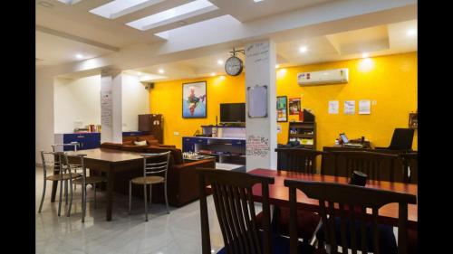 新德里Joey's Hostel Delhi的用餐室设有黄色的墙壁和桌椅