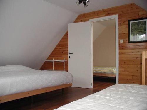 OpglabbeekDe Bosbeekpoort的一间卧室设有两张床,一扇门通往一个衣柜。