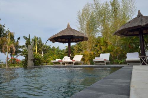 乌明亚丹妮逊别墅的度假村的游泳池,配有椅子和遮阳伞