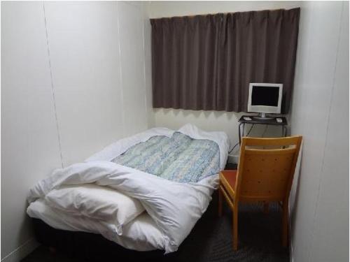 名古屋名古屋生态酒店的小卧室设有一张床和一张带电脑显示器的书桌