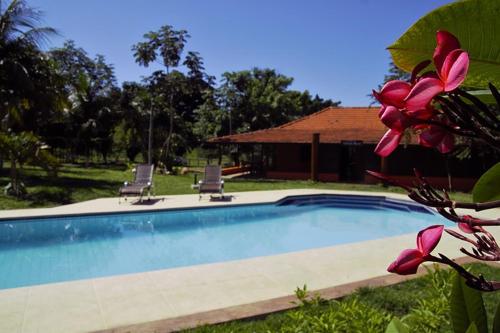 米兰达潘塔纳尔牧场梅亚鲁亚酒店的一个带两把椅子的游泳池以及一座房子