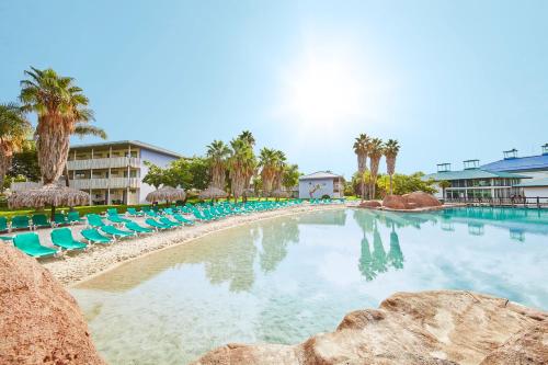 萨洛PortAventura Hotel Caribe - Includes PortAventura Park Tickets的一个带蓝色椅子和棕榈树的大型游泳池