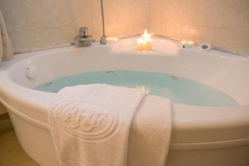圣弗朗西斯科尔坎姆弗诺罗浪漫酒店的浴缸配有2条毛巾和2把蜡烛