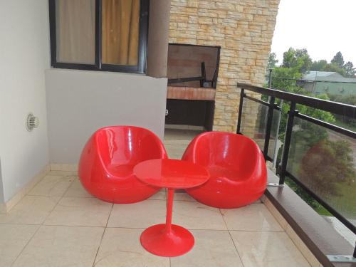 科隆Apartamento Brisas del Golf的阳台顶部设有两把红色椅子