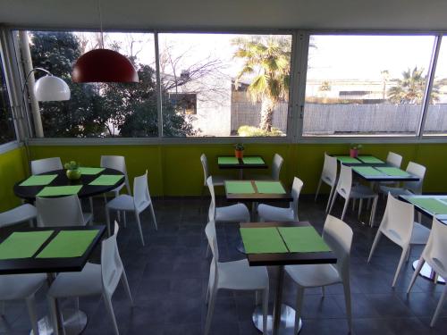 帕拉瓦莱弗洛蒙彼利埃南部海滩酒店的一间设有绿色桌子和白色椅子的餐厅