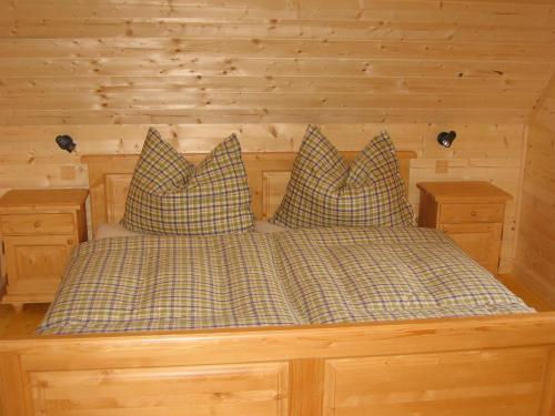 伊布斯河畔格施特灵Feriendorf Lassing的木制客房的一张床位,配有两个枕头