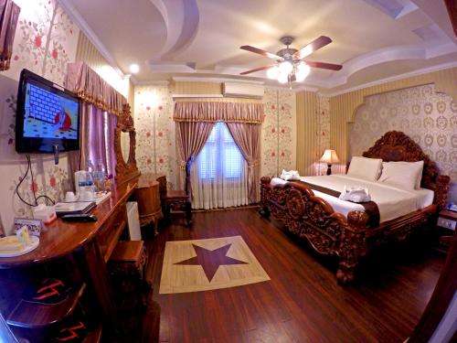 马德望国王风云酒店的一间卧室配有一张床、一张书桌和一台电视