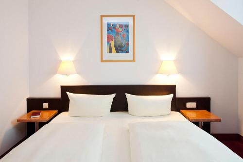 德累斯顿伽登乡村小别墅公寓式酒店的一间卧室配有一张带两盏灯的大型白色床。