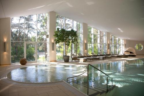 奥茨塞巴德·迪尔哈根菲林费斯兰德公寓的一座大型游泳池,位于一座带窗户的建筑内