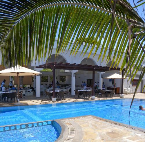 迪亚尼海滩马缨丹嘎鲁海滩酒店的一个带桌椅和遮阳伞的游泳池