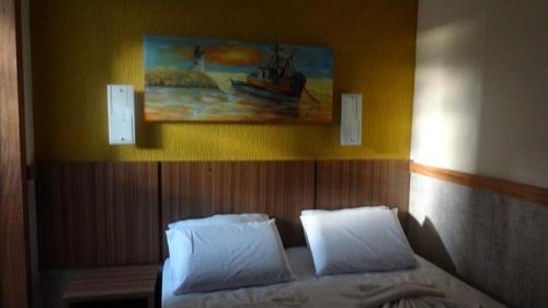 塞古罗港Ancoradouro Hotel - Centro De Porto Seguro的一间卧室配有带两个枕头的床和一幅画
