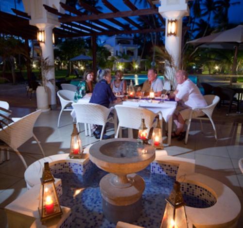 迪亚尼海滩马缨丹嘎鲁海滩酒店的一群人坐在餐馆的桌子旁