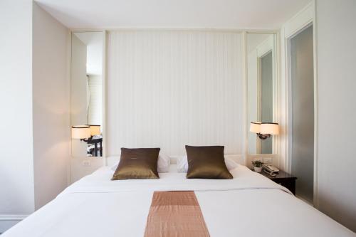 曼谷曼谷阿芙罗宾馆的卧室配有带棕色枕头的大型白色床