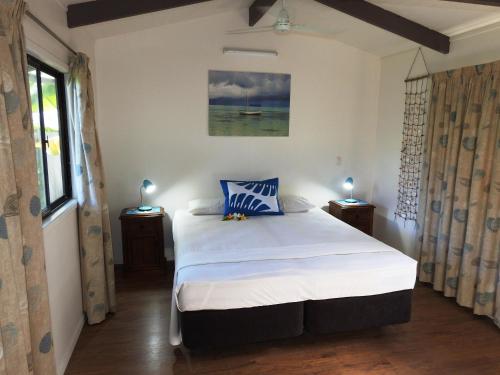 拉罗汤加阿莱曼格宾馆的卧室配有带蓝色枕头的大型白色床