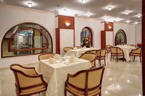 布拉索夫Hotel Citrin - Adults Only的一间设有白色桌椅的用餐室