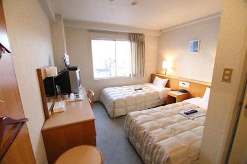 高知South Breeze Hotel Kochi Kaigetsu的酒店客房设有两张床和电视。