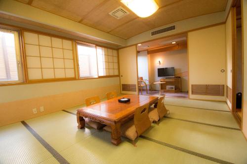 高知South Breeze Hotel Kochi Kaigetsu的一间带木桌和椅子的用餐室