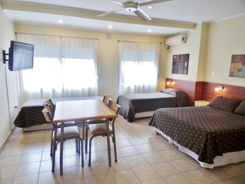 布兰卡港Apartamentos Güemes - Monoambientes的一间酒店客房,设有两张床、一张桌子和一台电视机