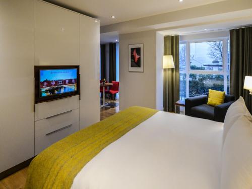 都柏林PREMIER SUITES Dublin, Ballsbridge的配有一张床和一台平面电视的酒店客房