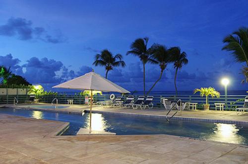 克里斯琴斯特德圣克罗伊海滩俱乐部网球度假酒店的一个带椅子和遮阳伞的游泳池以及大海