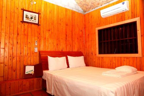 吉婆岛自然细语洋房及度假酒店的卧室配有木墙内的一张床