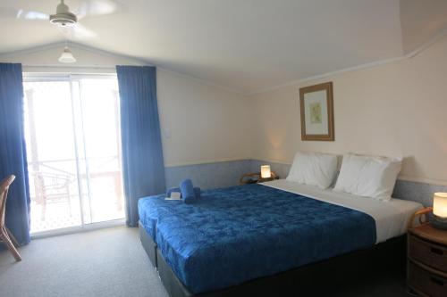 飞鱼湾日落酒店的一间卧室配有一张带蓝色毯子的大床