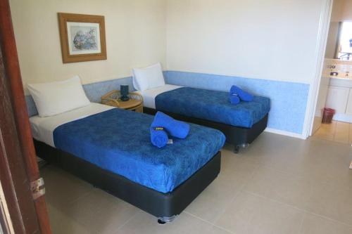 飞鱼湾日落酒店的客房内的两张床和蓝色床单