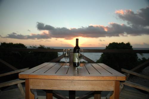飞鱼湾日落酒店的一张木桌,配有一瓶葡萄酒和两杯酒