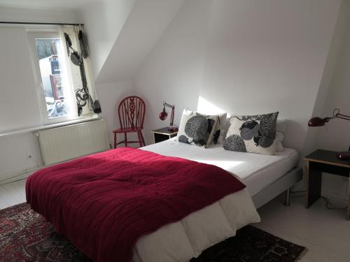 迪南小丽丽度假屋的一间卧室配有一张带红色毯子的床和窗户。