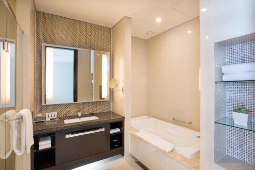金海市I广场酒店的一间带水槽、浴缸和镜子的浴室