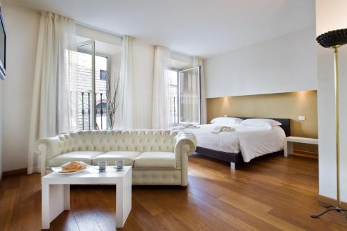 佛罗伦萨瑞雷斯广场酒店的一间卧室配有一张床、一张沙发和一张桌子