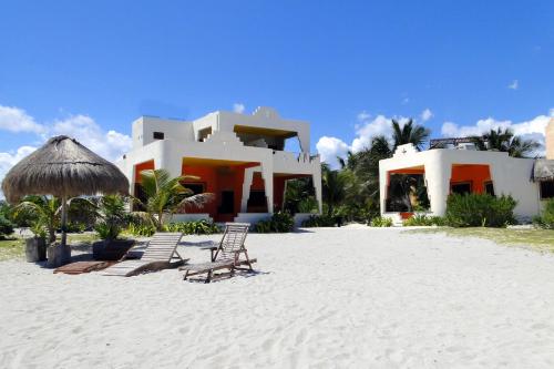 El PlacerMayan Beach Garden的海滩上的房子,配有椅子和遮阳伞