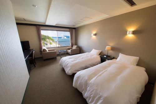 鸣门市太马路海边酒店的酒店客房设有两张床和窗户。