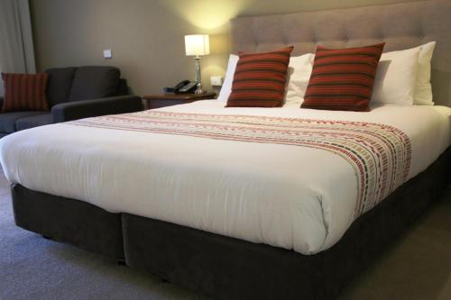 巴拉腊特钟楼旅馆的一张大床,配有红色枕头,位于酒店客房内